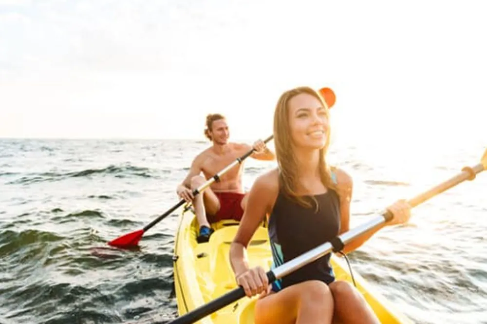 Active couple kayaking at sunset, living life well