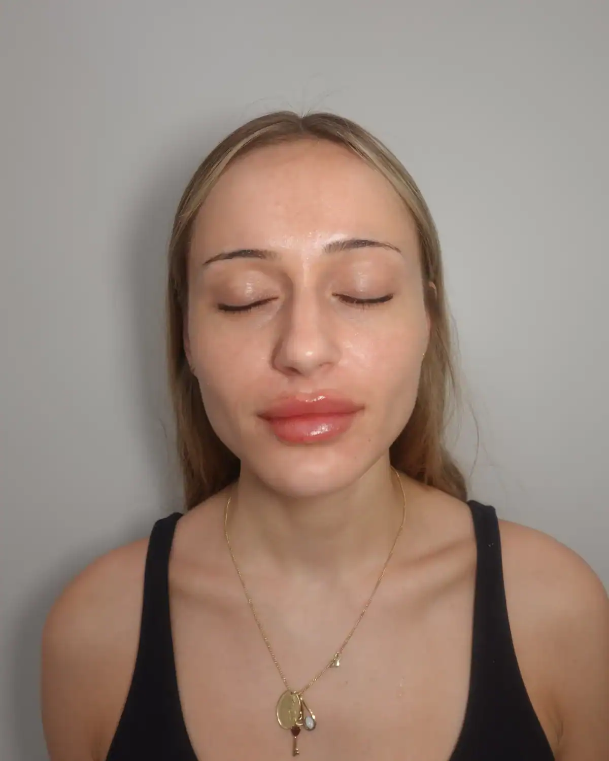 Woman with closed eyes and relaxed expression in a skincare setting.